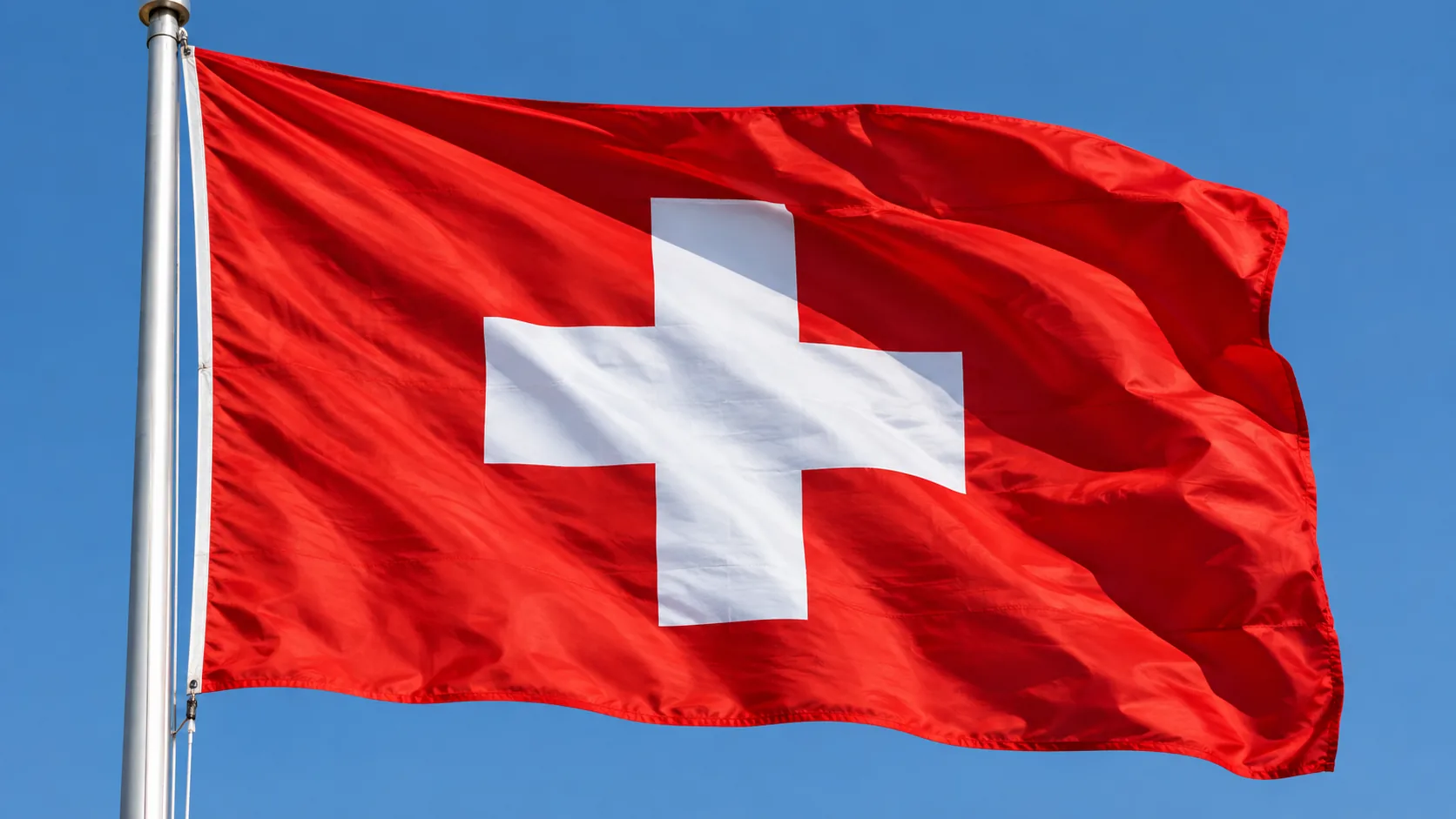 Swiss flag waving against a clear blue sky